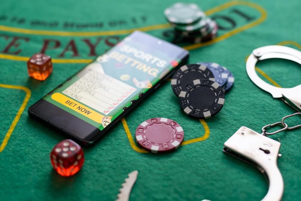 Law and rules for online casino concept, smartphone with handcuffs and playing chips