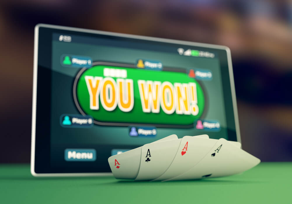 closeup view of a tablet pc with a poker app on winning situation and four aces